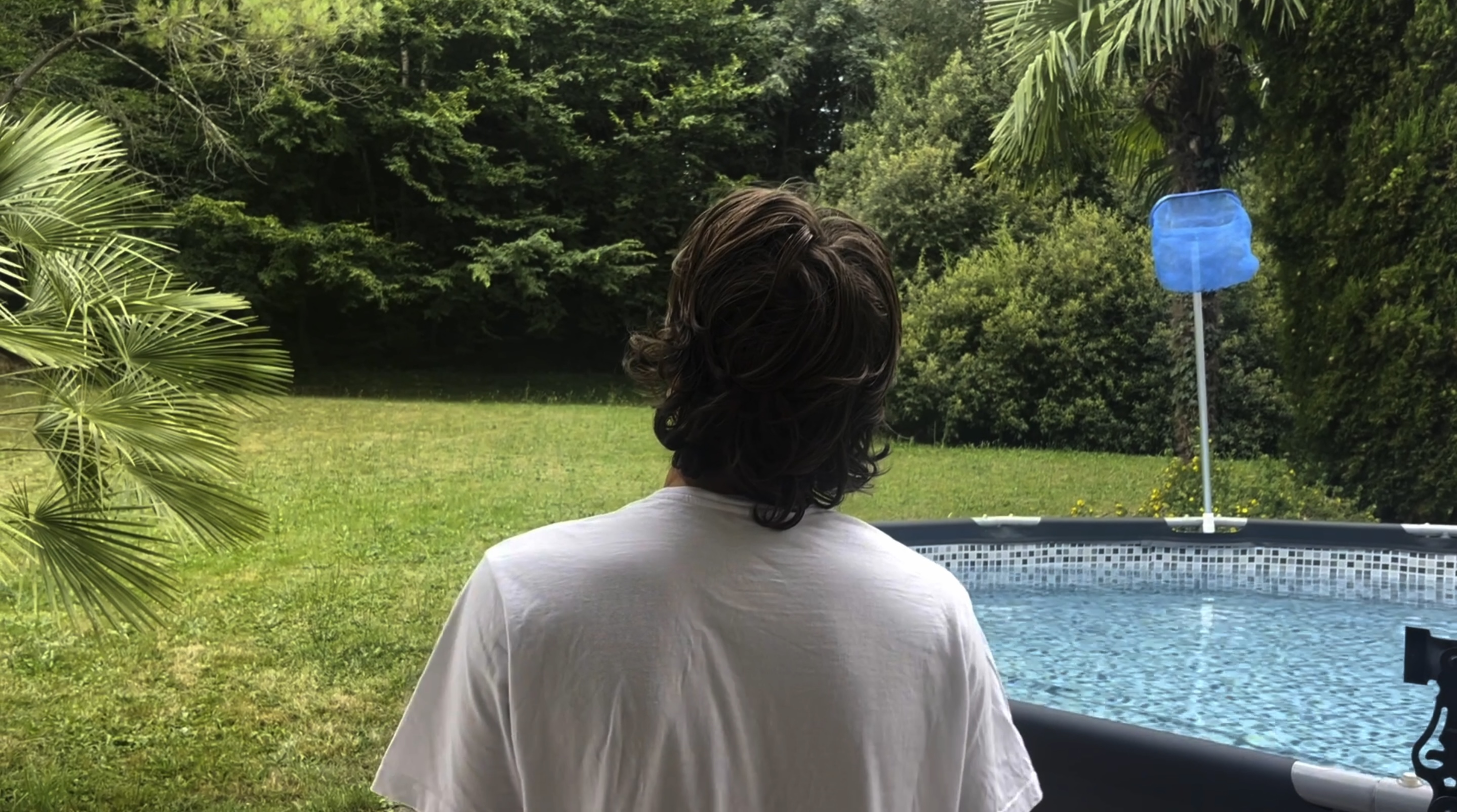 Image tirée de Psychical Pearls où un homme vu de dos contemple la forêt qui se trouve devant lui. À droite de lui se trouve une piscine.